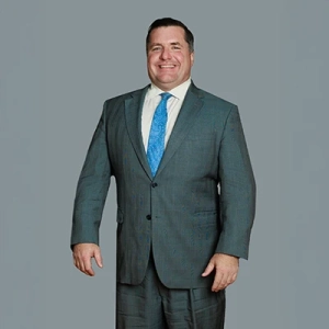 Man in a suit smiling against a plain background