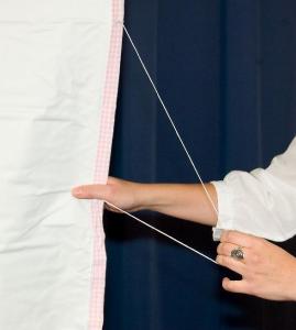 A person adjusting a fabric with a string attached