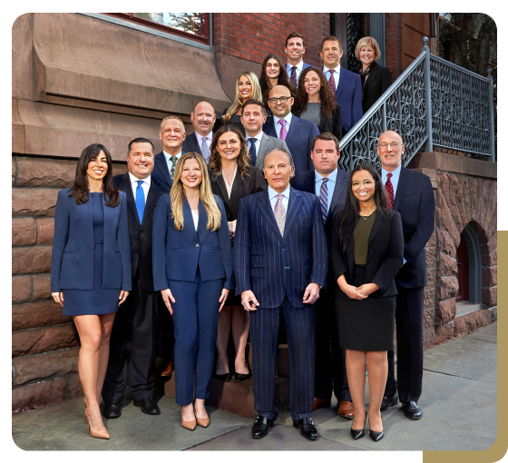 Group portrait of a diverse legal team standing on steps of a building, dressed in professional attire.